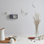 Haoshi Sparrow Clock in Dark Gray color on a grey wall with table ware accessories beside a vase available at Spacio india for modern and luxury interiors from our Timepieces and clocks collection.