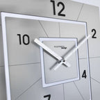 Modern wall clock with square design and white frame on a tiled wall.