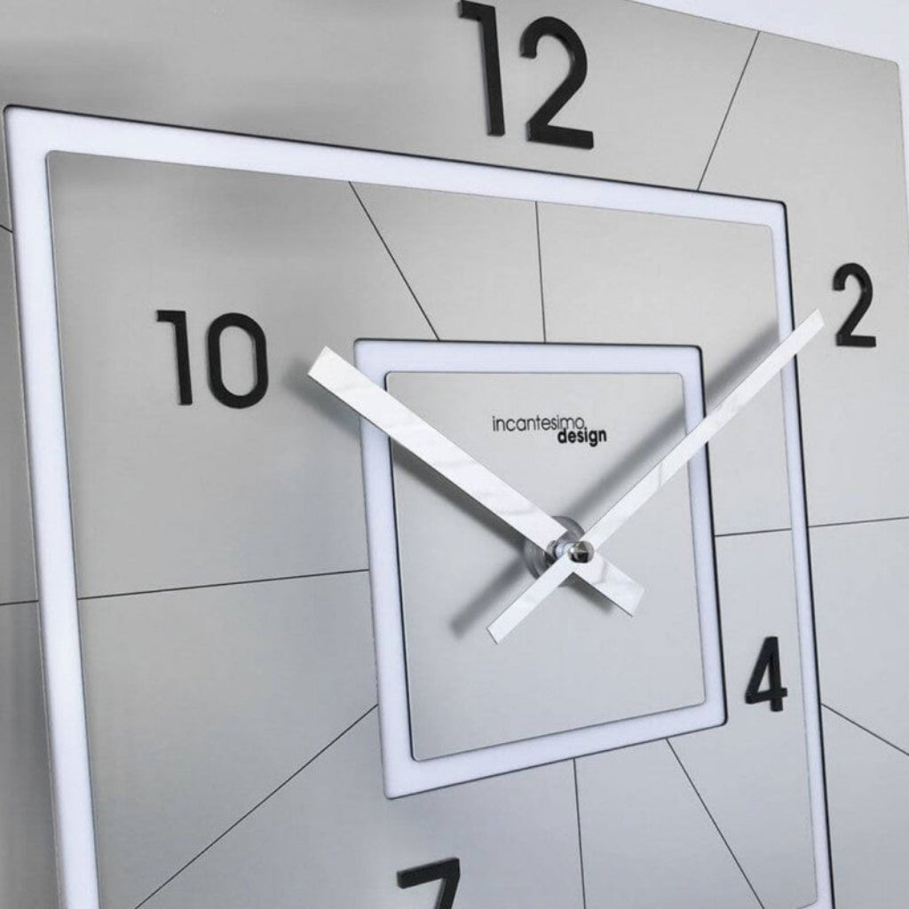 Modern wall clock with square design and white frame on a tiled wall.