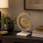 Decorative sundial design table clock on a wooden surface with books and a plant in the background