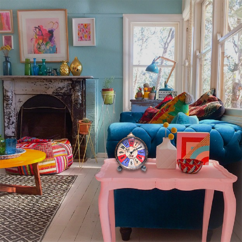 Colorful living room with blue sofa, pink table, and various decor items.