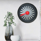Modern wall clock with red秒针 on a white wall, next to a vase with greenery.