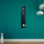 Digital clock on a teal wall with a vase and lamp in the foreground