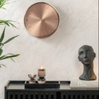 Decorative wall clock and sculpture on a shelf with a marble wall background