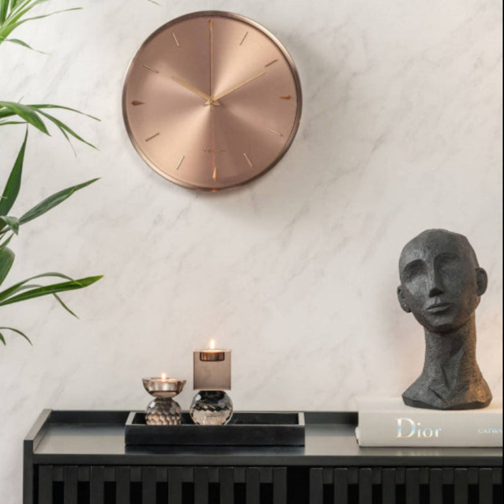 Decorative wall clock and sculpture on a shelf with a marble wall background