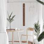 Small dining area with a round table, chair, and plants against a white wall.