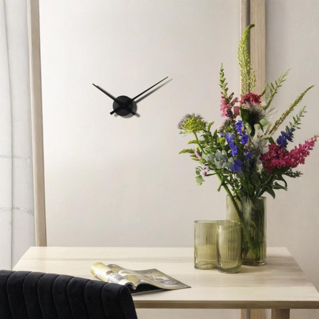 Modern wall clock on a white wall with a vase of flowers and a candle on a table.