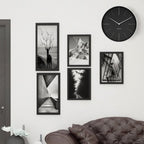 Wall with framed black and white photos and a clock above a sofa