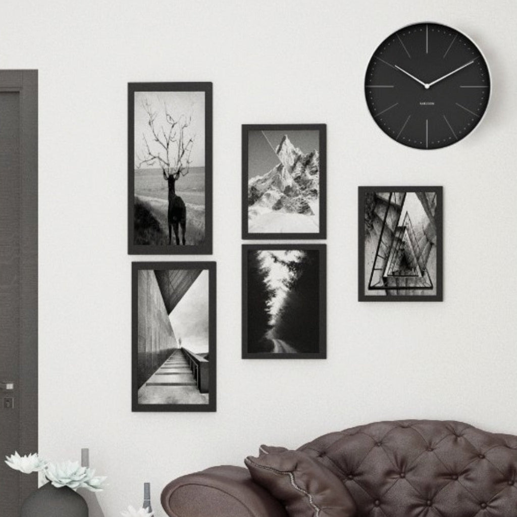 Wall with framed black and white photos and a clock above a sofa