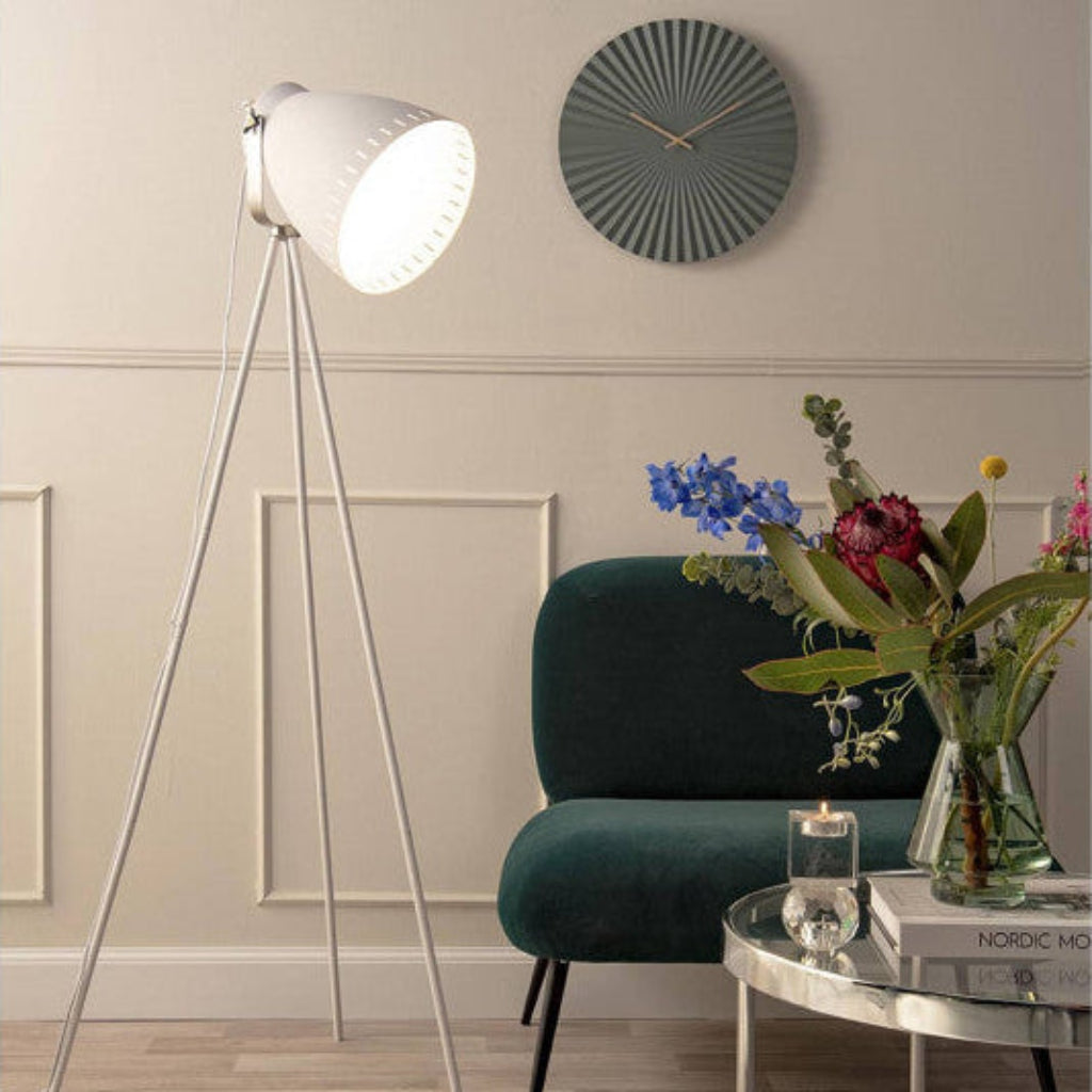Modern living room with a tripod floor lamp, green armchair, and decorative items.