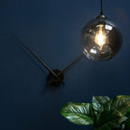 Modern wall-mounted light fixture with a glass globe on a dark blue wall.