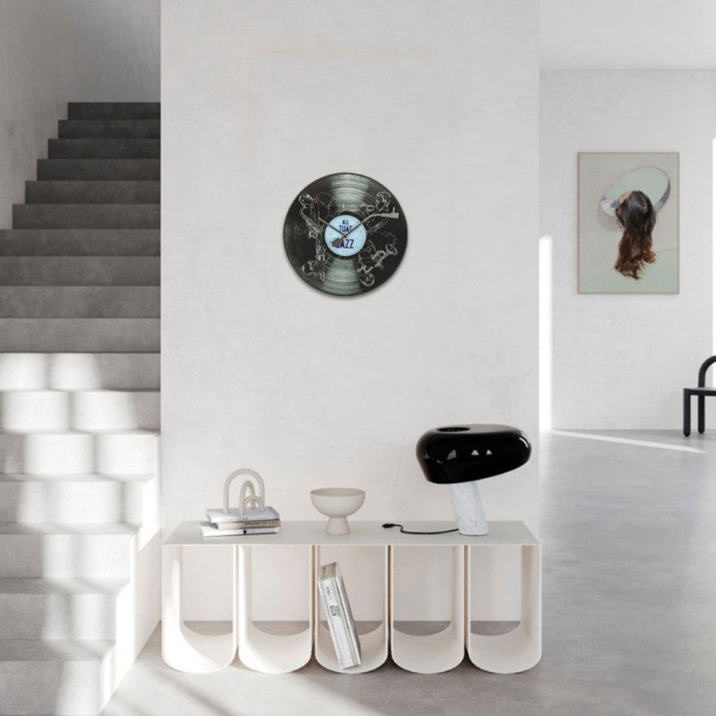 Modern interior with a vinyl record wall clock, white console table, and staircase.