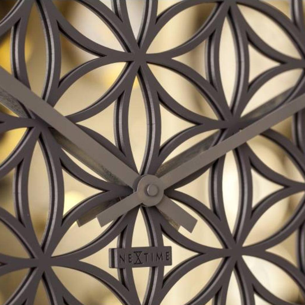 Decorative wall clock with intricate design and brand name on a white background