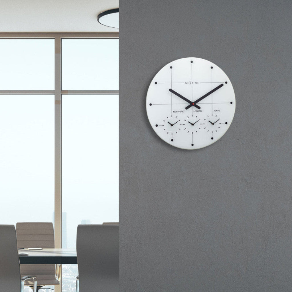 Wall clock on a gray wall with a meeting room in the background