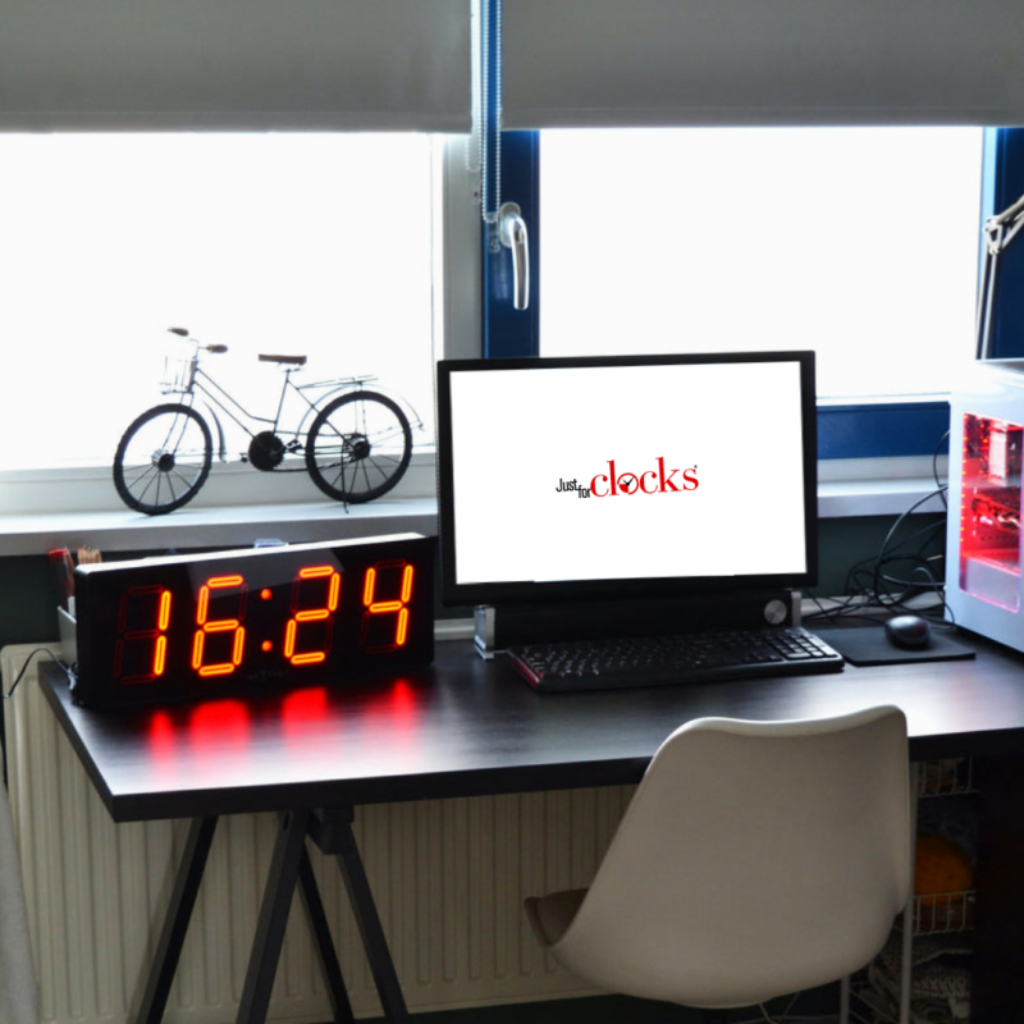 Digital clock displaying time on a desk with computer setup