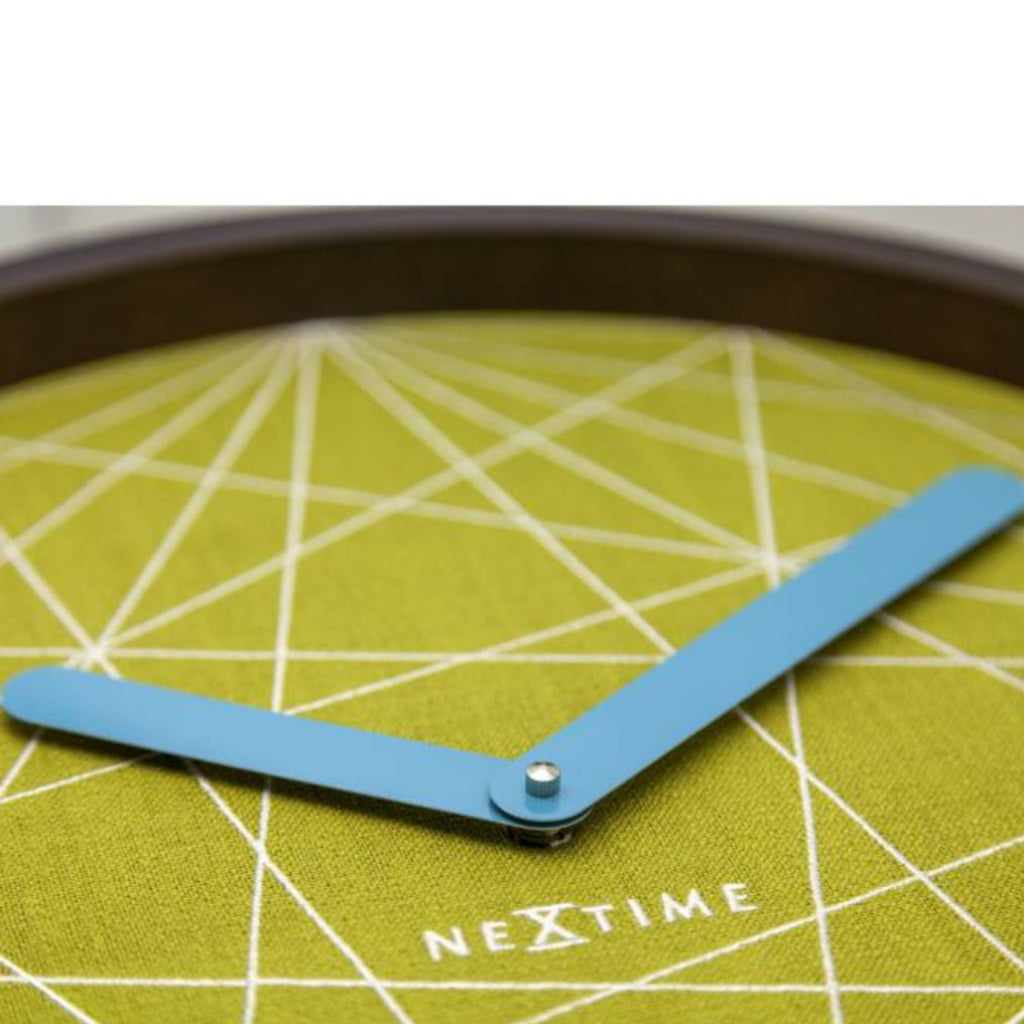 Close-up of a wall clock with a green geometric pattern and blue hands, branded 'Nextime'.
