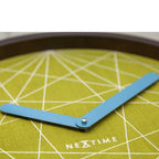 Close-up of a wall clock with a green geometric pattern and blue hands, branded 'Nextime'.
