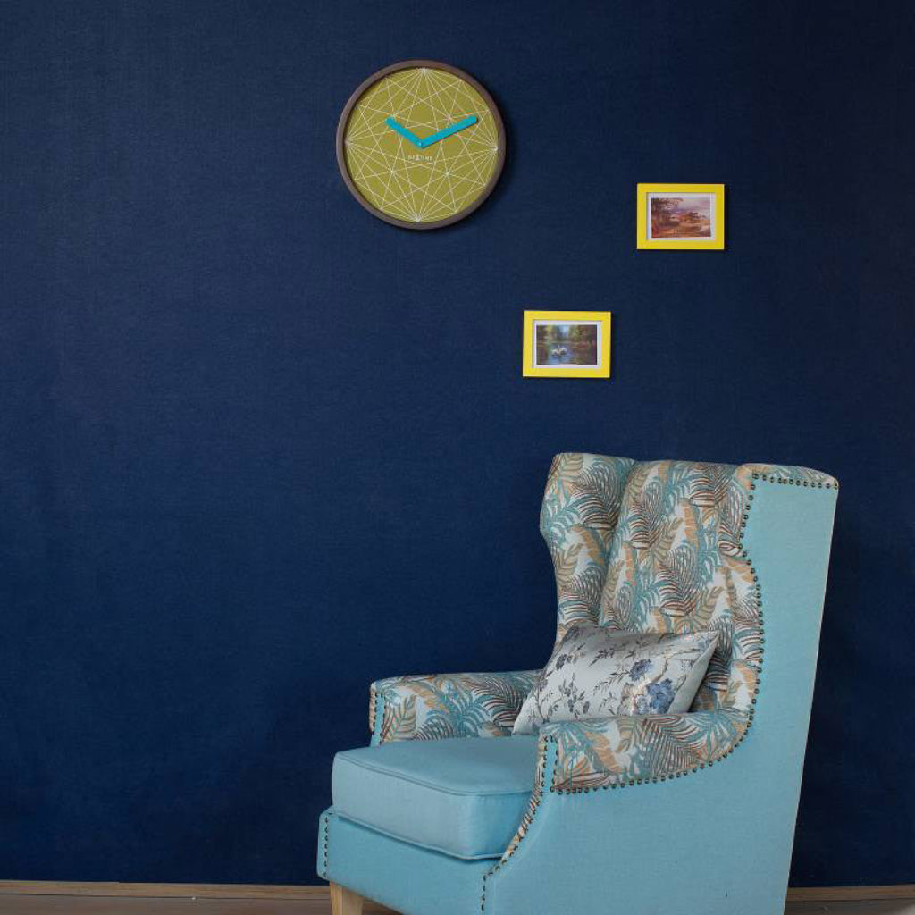 Blue armchair against a dark blue wall with decorative elements.