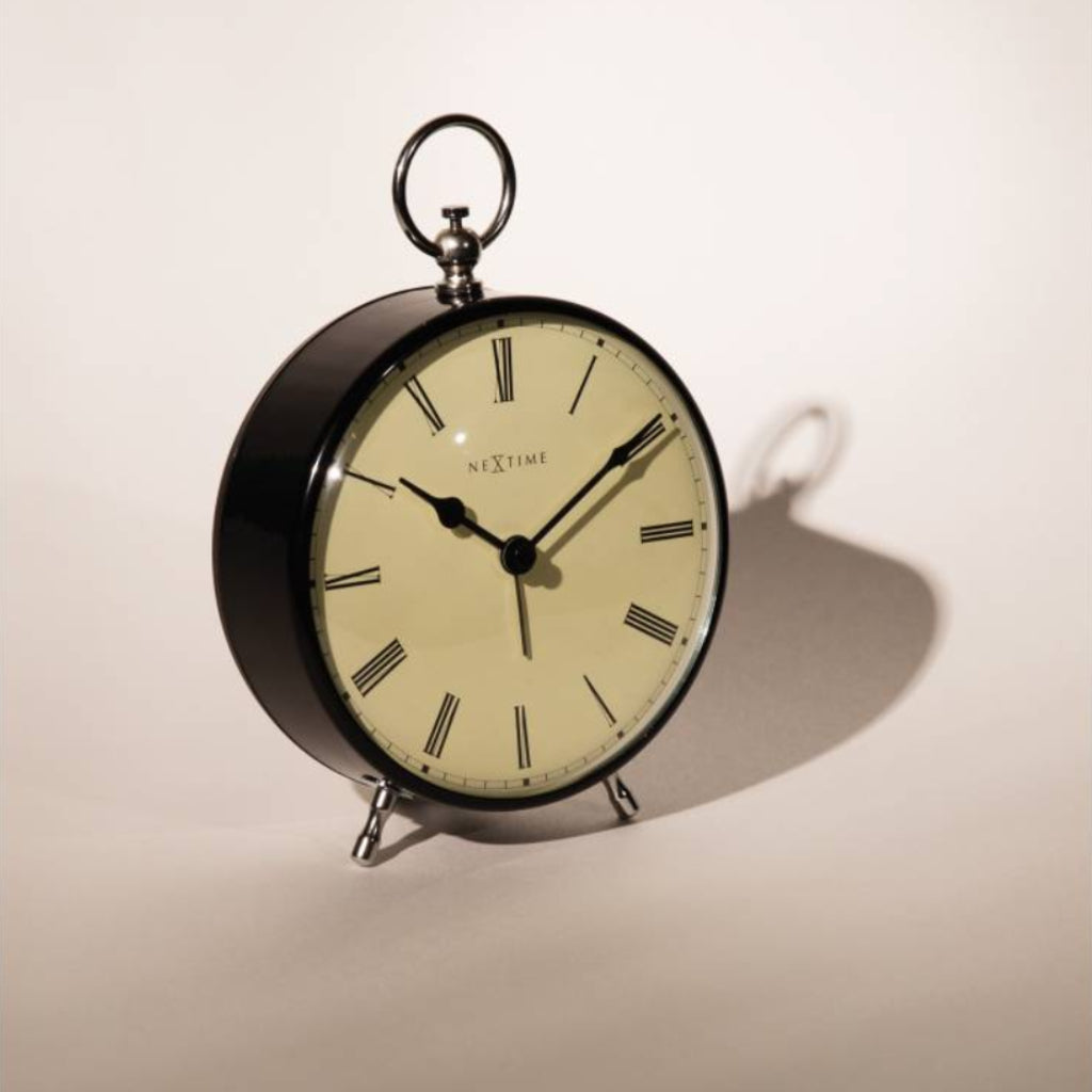 Round table clock with black frame and beige face on a light background