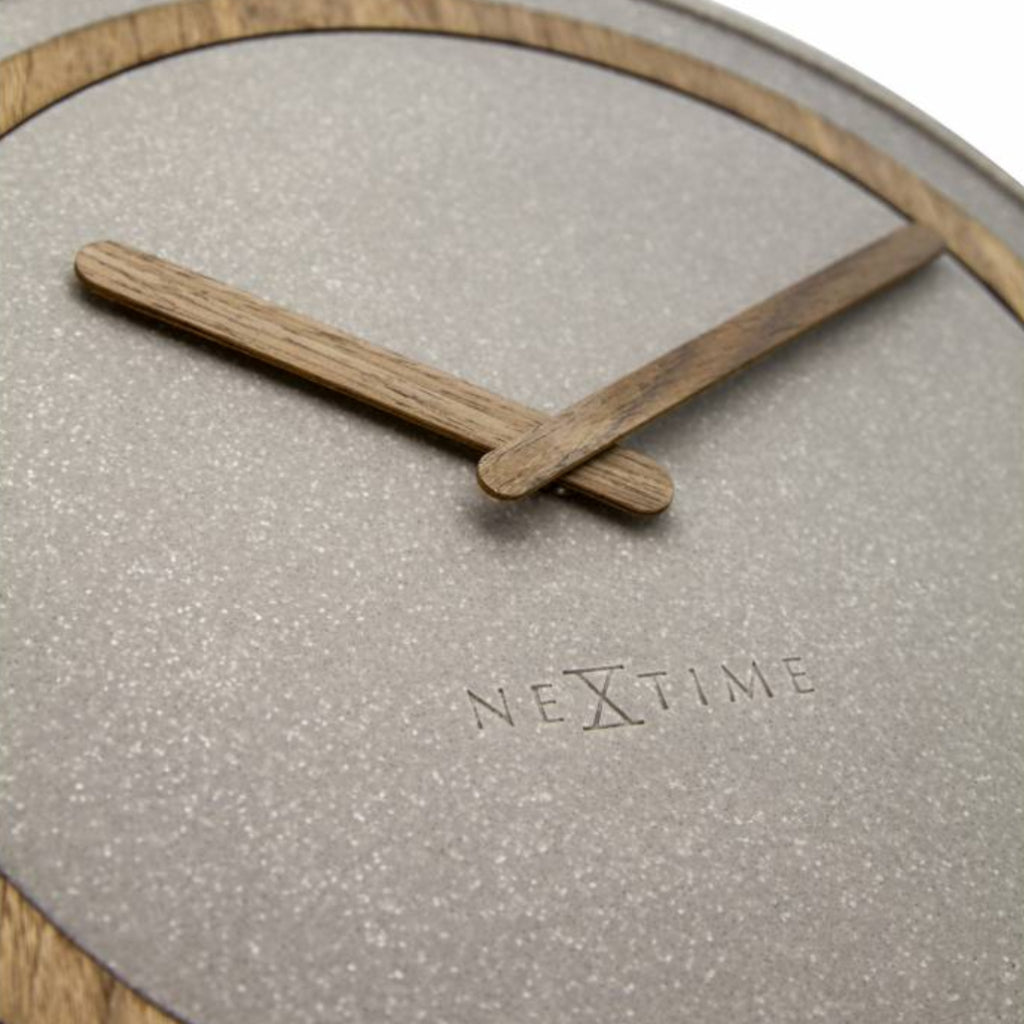 Close-up of a clock with wooden hands and 'Nextime' branding on a light gray background.
