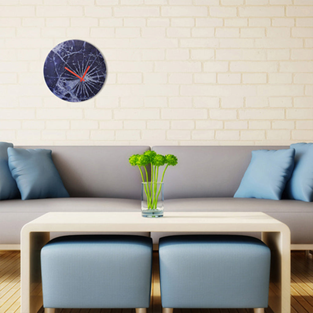Modern living room with a gray sofa, blue cushions, a wooden coffee table, and a decorative clock on the wall.