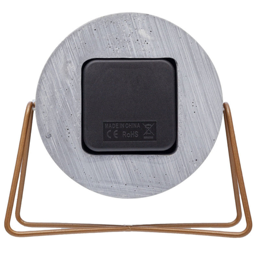 Round concrete-like object with a black square label and bronze frame on a white background