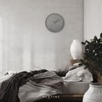 Bedroom with a clock on the wall, bed with gray bedding, and decorative elements.