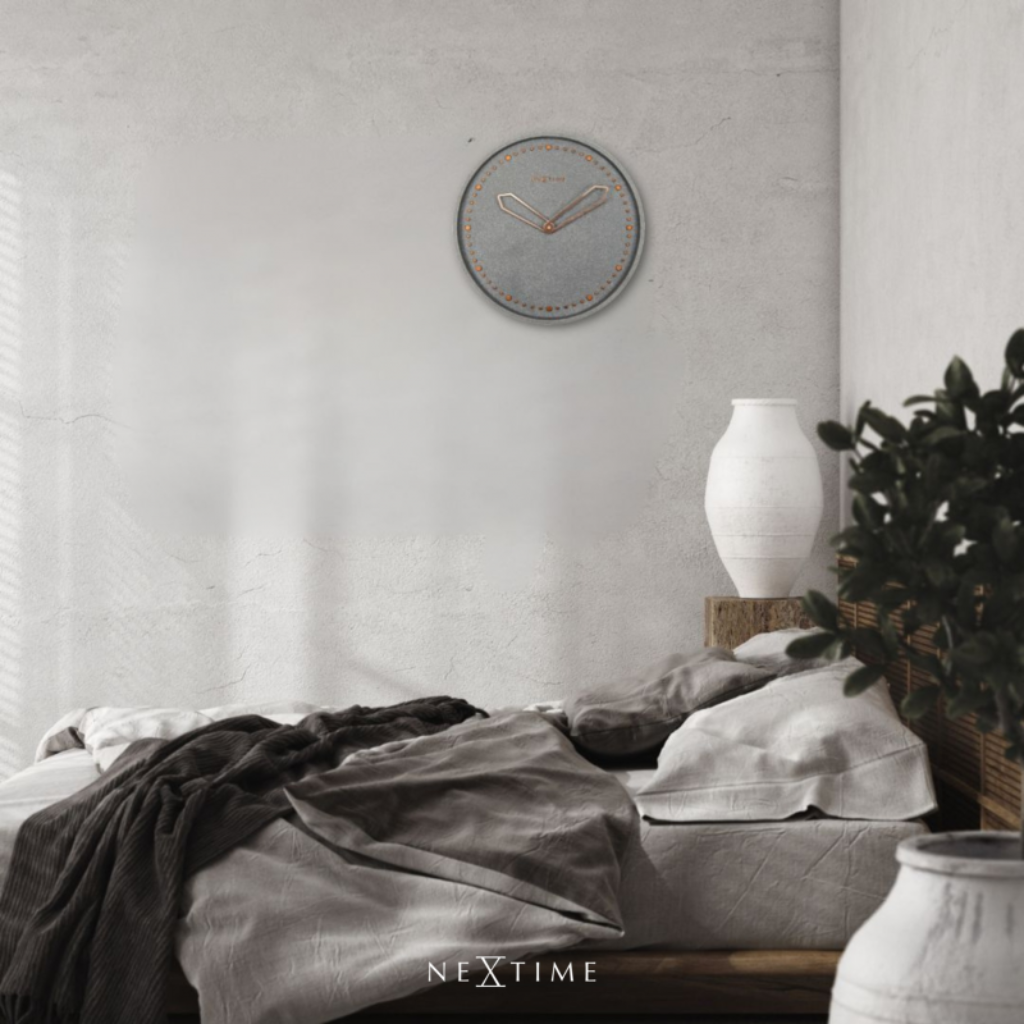 Bedroom with a clock on the wall, bed with gray bedding, and decorative elements.
