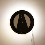 Round wall light fixture with control buttons on a beige wall