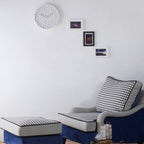 Navy blue armchair with checkered cushions and ottoman in a room with framed pictures on the wall.