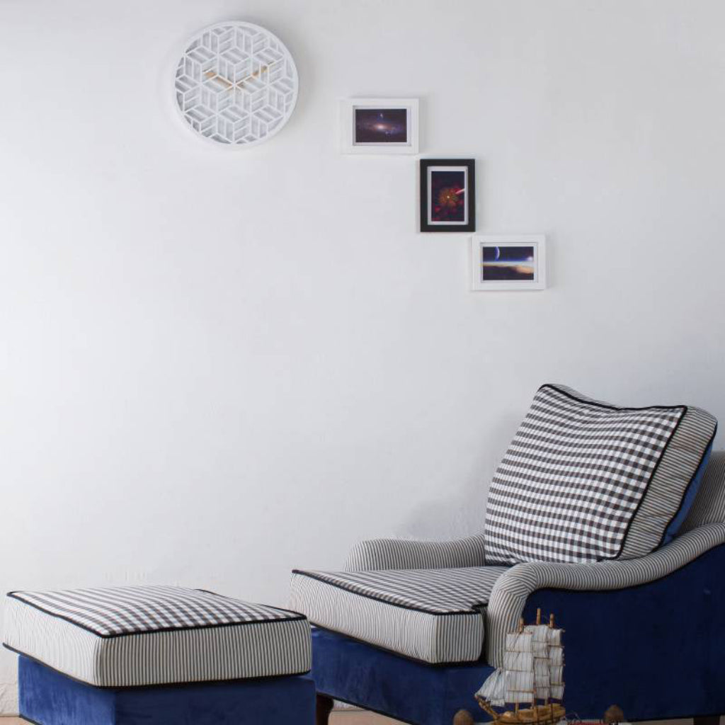 Navy blue armchair with checkered cushions and ottoman in a room with framed pictures on the wall.