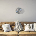 Brown sofa with decorative pillows and a wall clock in a minimalistic room.