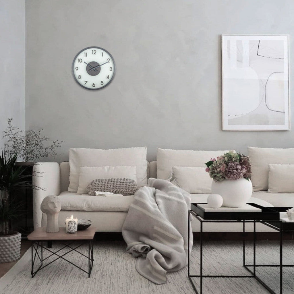 Modern living room with a white sofa, decorative pillows, and a wall clock.