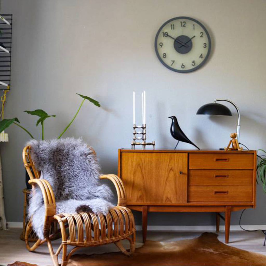 Living room with wooden sideboard, wicker chair, and decorative items.
