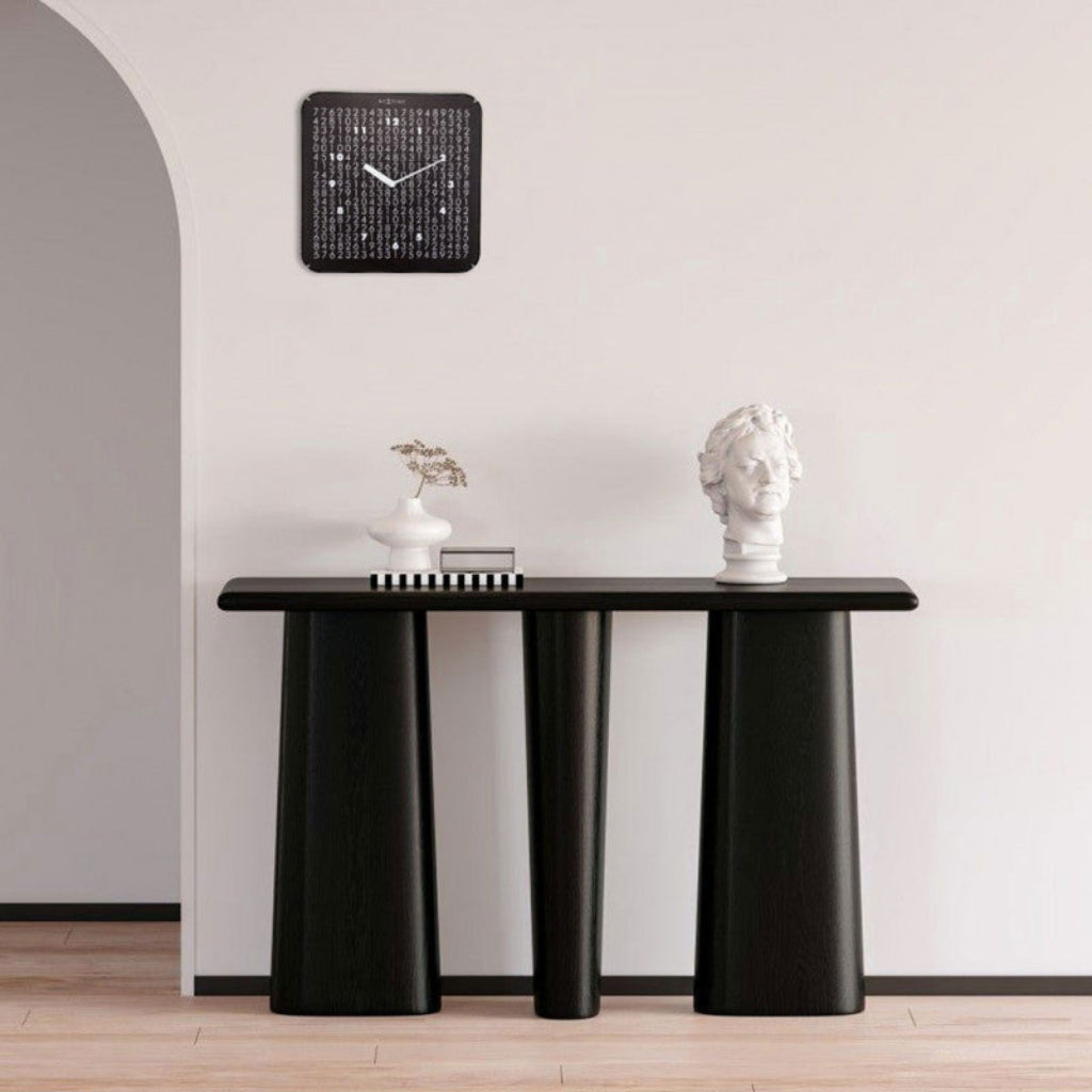 Modern black console table with decorative items against a white wall.