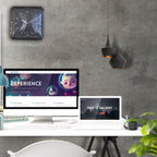 Modern office desk with computer monitors displaying website interfaces against a concrete wall.