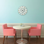 Round table with two pink chairs against a light blue wall with a decorative clock.
