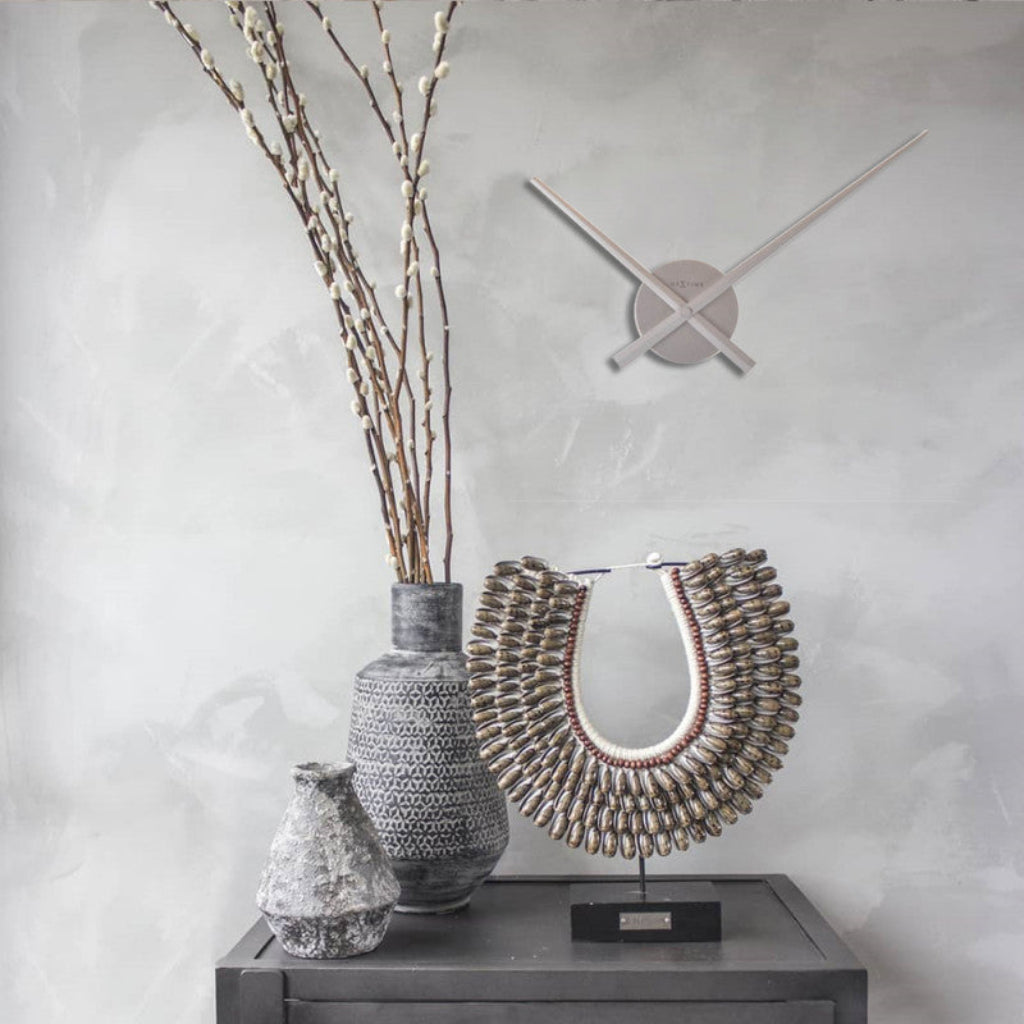 Decorative vases and wall clock on a gray surface with a light gray background