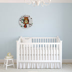 White crib in a room with a light blue wall and owl decor.
