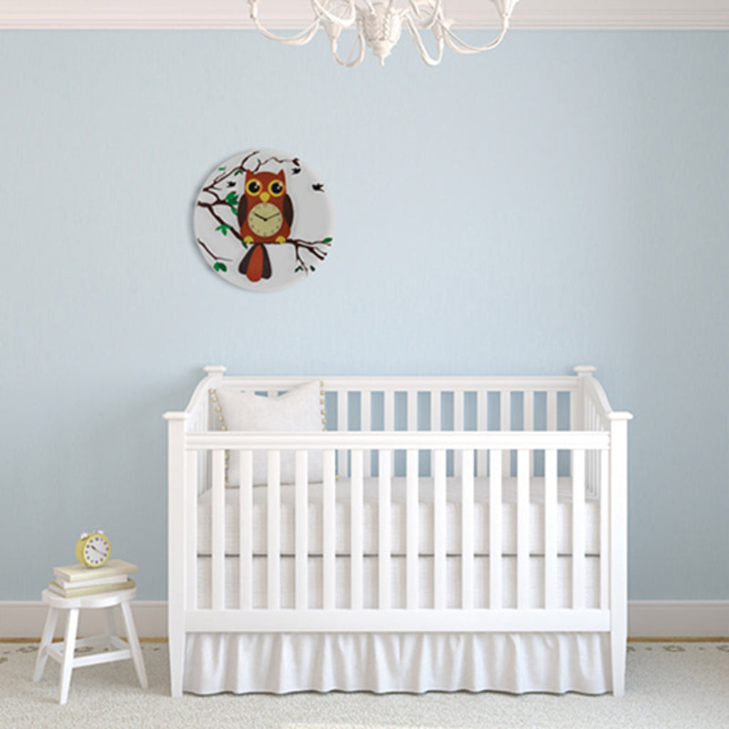 White crib in a room with a light blue wall and owl decor.