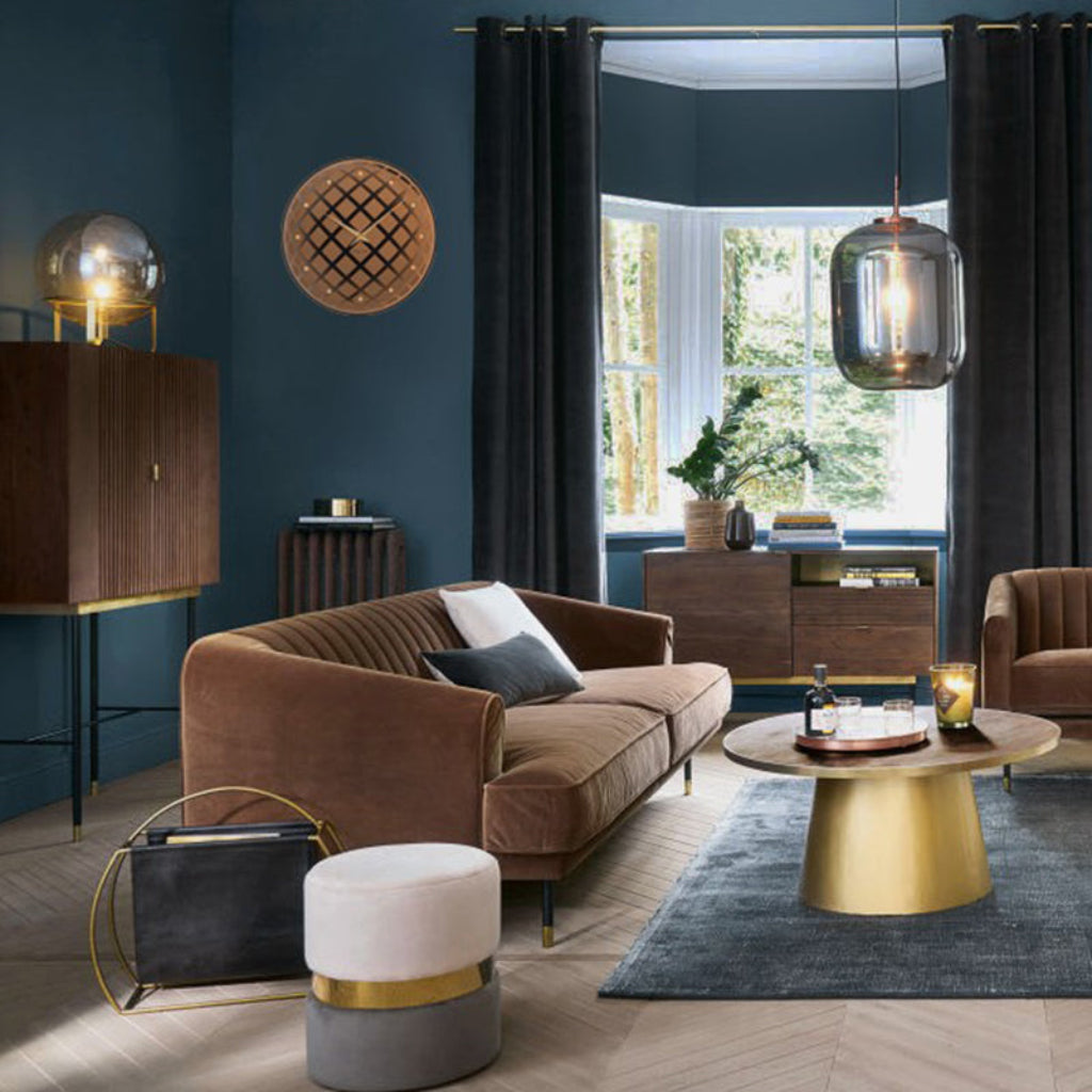 Modern living room with brown sofa, gold coffee table, and decorative elements.
