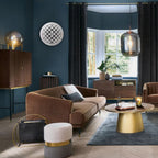 Modern living room with brown sofa, gold coffee table, and decorative elements.