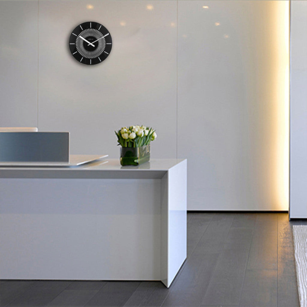 Modern office reception area with a white desk, flower vase, and clock on the wall.