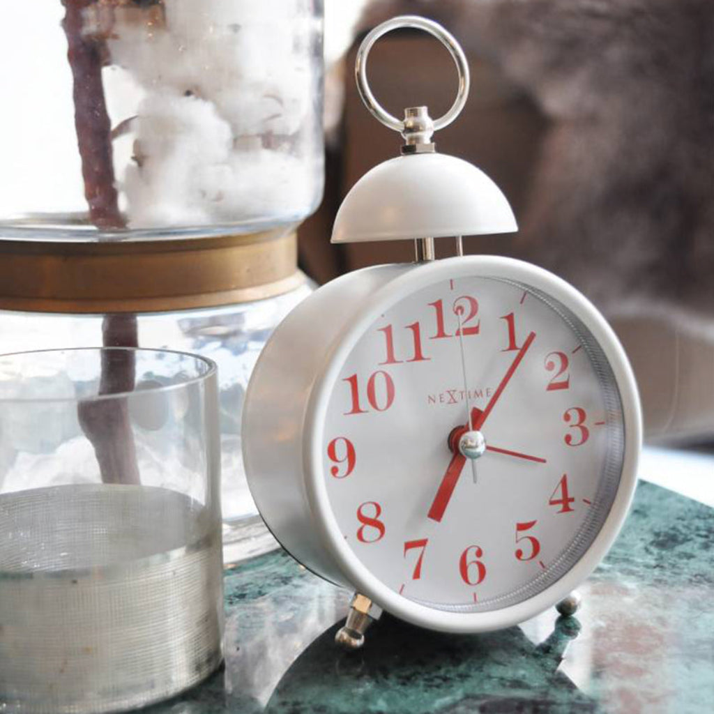 White alarm clock with red numbers on a decorative surface