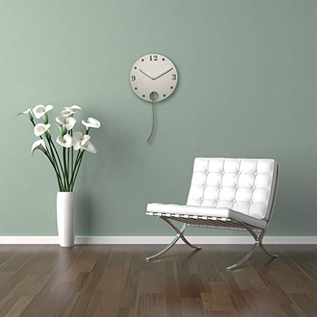 Modern interior with a white chair, vase of flowers, and wall clock on a light green wall.