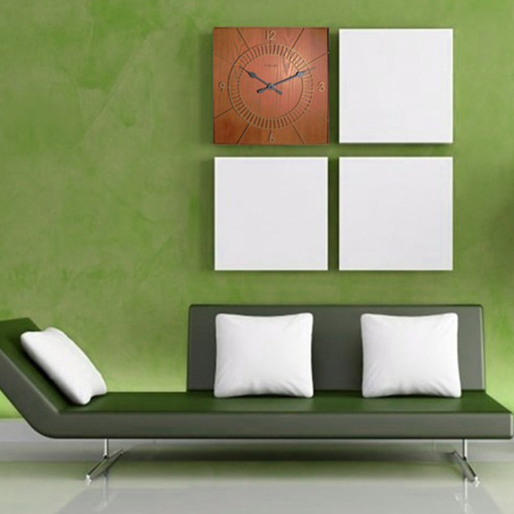 Green wall with a clock and white square decorations, featuring a green sofa with white pillows.