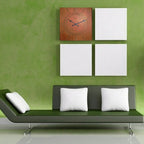 Green wall with a clock and white square decorations, featuring a green sofa with white pillows.