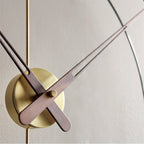 Modern wall clock with gold casing and wooden hands on a light gray background