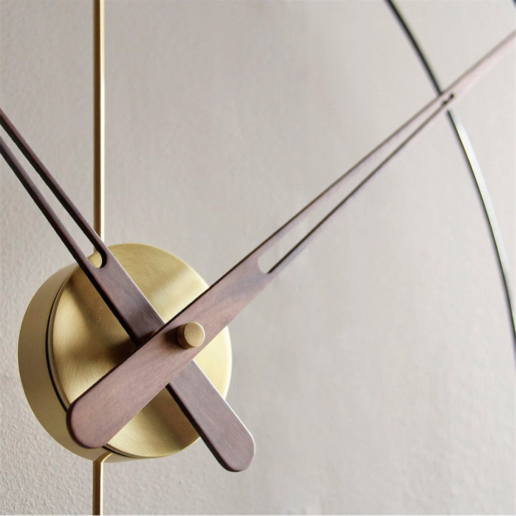 Modern wall clock with gold casing and wooden hands on a light gray background