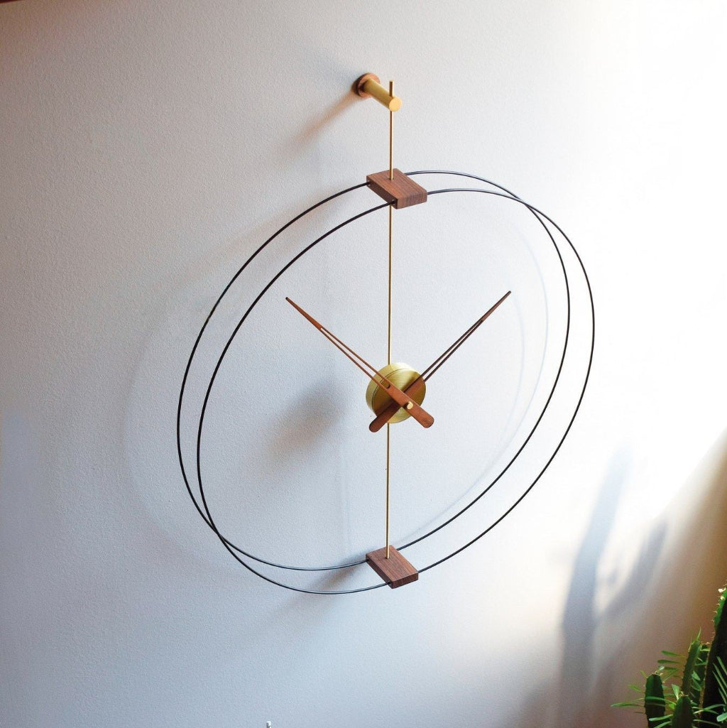 Modern wall clock with gold and wood accents on a white wall